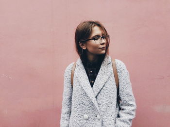 Beautiful young woman standing against wall