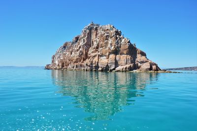 Low angle view of rock formation at sea against blue sky