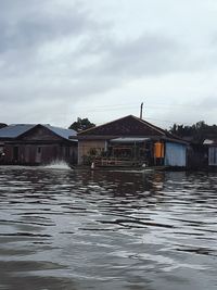 Houses by lake against sky