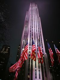 Low angle view of american flags and illuminated tower against sky at night