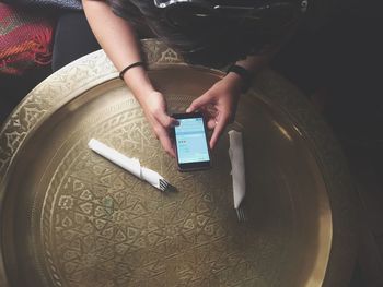 High angle view of woman using mobile phone by empty plate at restaurant