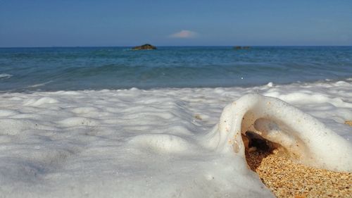 Close-up of surf on beach against sky