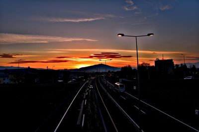 Highway tracks in city against sky during sunset