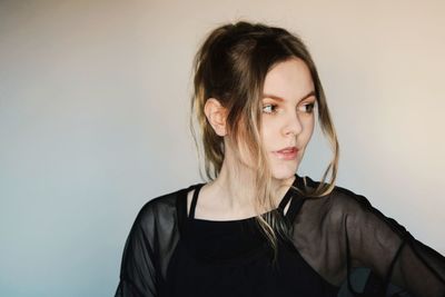 Portrait of beautiful young woman against wall