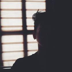 Close-up of man against window blinds at home