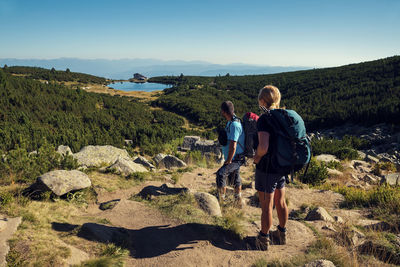 Friends hiking on mountain against clear sky