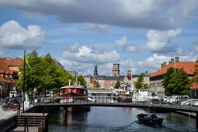 Bridge over river by buildings in city against sky