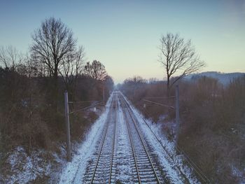 View of railroad tracks along bare trees in winter