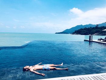 People relaxing in sea against sky