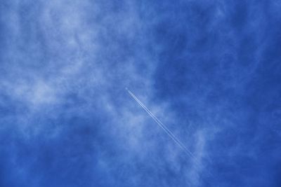 Low angle view of vapor trail against blue sky