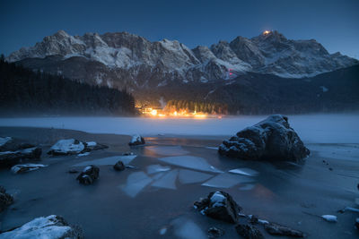 Scenic view of frozen lake by mountains against sky