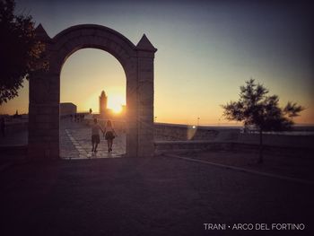 Silhouette people on bridge against clear sky during sunset