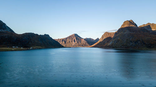 Scenic view of sea and mountains against clear blue sky