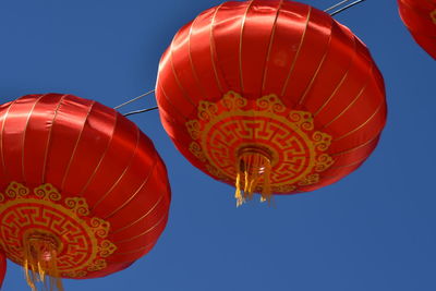 Low angle view of lanterns hanging against clear blue sky