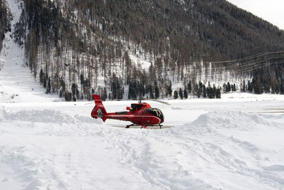 A red airport helicopter in the snow in the alps switzerland