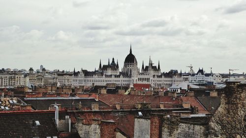 Buildings in city against cloudy sky