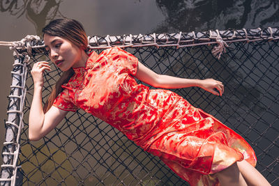 Midsection of woman looking at metal fence