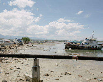 Boat moored on beach against sky