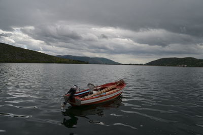 Boats in lake against cloudy sky