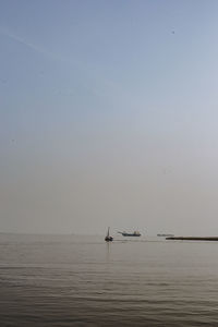 Sailboat in sea against clear sky