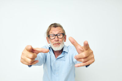 Portrait of smiling senior man gesturing against white background