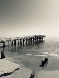 Wooden posts in sea against clear sky