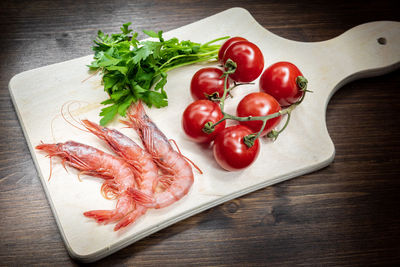 High angle view of shrimps by tomatoes on cutting board