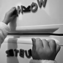 Cropped image of child hand playing with letter magnet on refrigerator