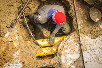 High angle view of man digging in sewer