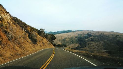 Country road by mountain against sky