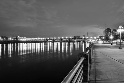 Illuminated pier over sea against sky at night