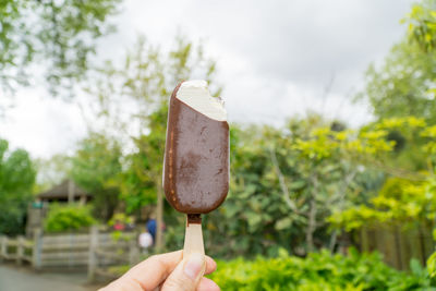 Hand holding ice cream cone against blurred background