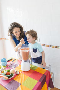 Woman preparing food while standing with son