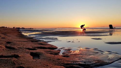 Silhouette man standing at beach against clear sky during sunset