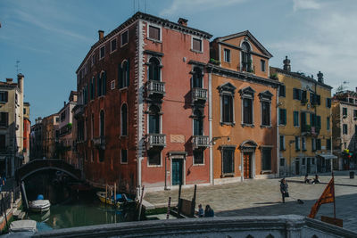 Buildings by canal against sky in city