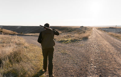 Hunter man is walking with the shotgun on his shoulder