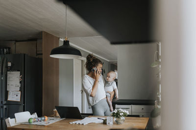 Multitasking mother taking care of baby and working from home