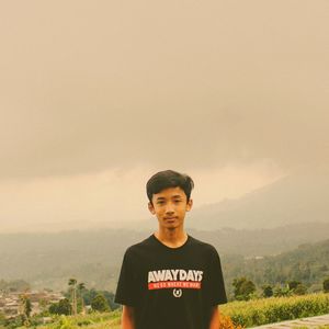 Portrait of young man standing against sky