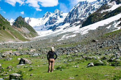 Full length of woman walking on field against snowcapped mountains