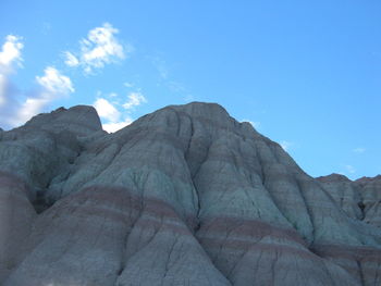 Low angle view of rocky mountains against blue sky