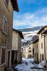 Snow covered houses by buildings against sky