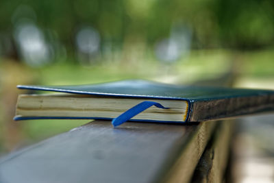 Close-up of book on wooden railing