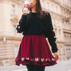 Midsection of woman holding red umbrella standing in city