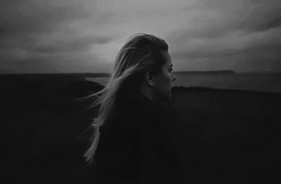 Young woman standing at beach against sky