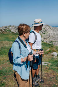 Side view of senior couple standing on land against clear sky