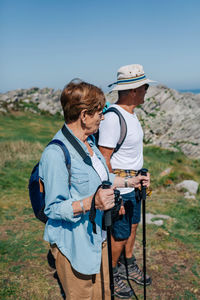 Rear view of friends standing on land against sky