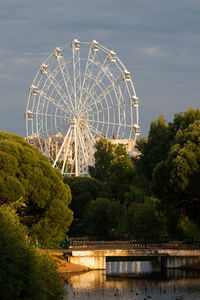 Ferris wheel by lake against sky