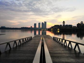 Scenic view of river by buildings against sky during sunset