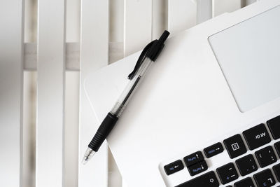 Black pen on top of a white laptop.