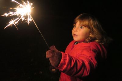 Scared girl holding sparkler at night